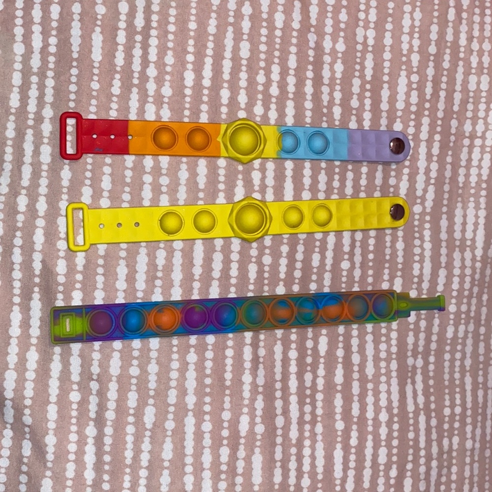 Three pop it bracelets. Good pops. One yellow one rainbow and one multi colored